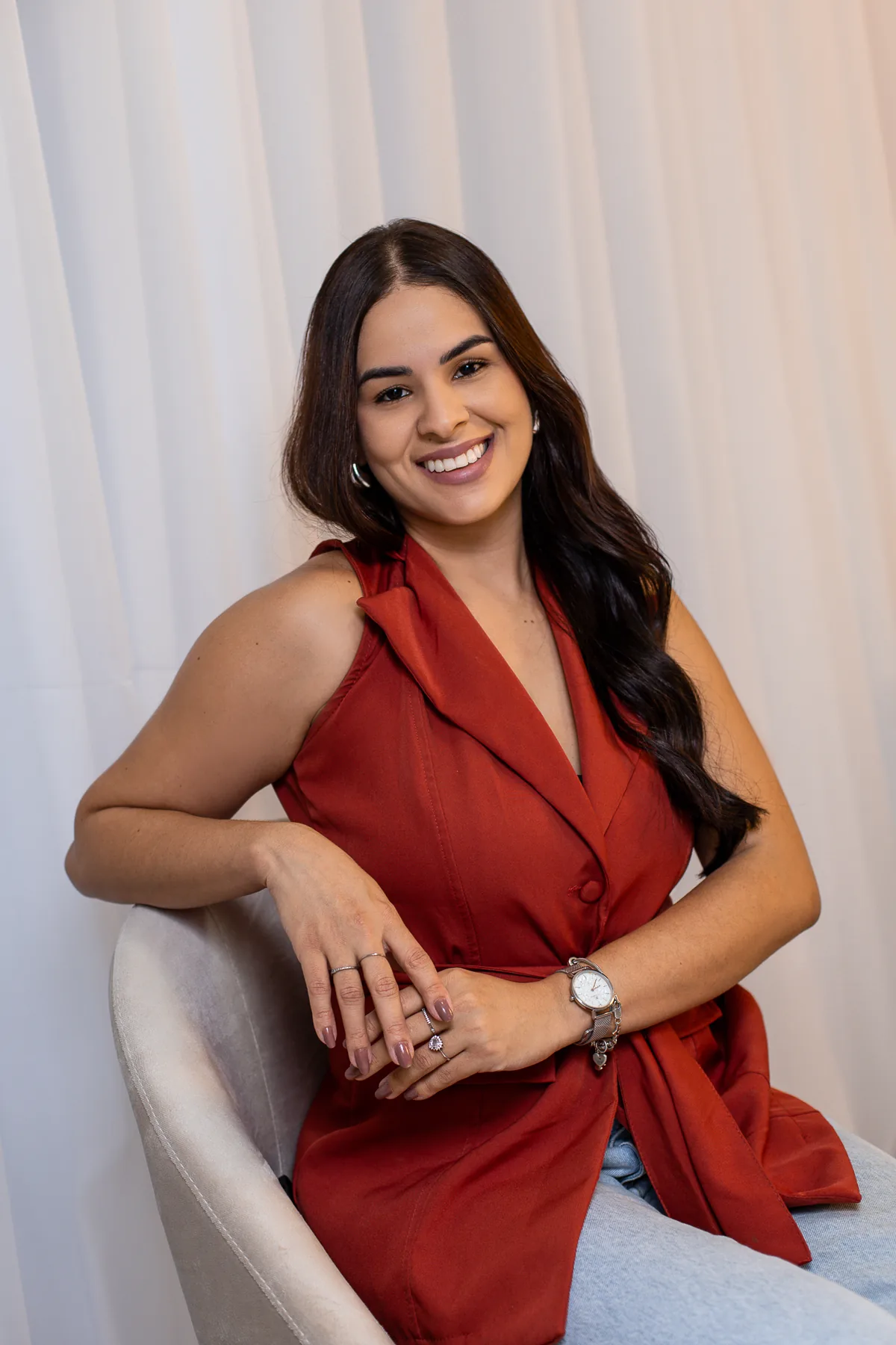 Mislley Santos sentada em uma poltrona, sorrindo para a câmera.
